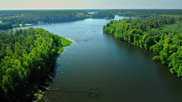 River between green forests, aerial view of Poland