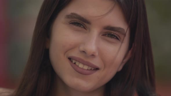 Closeup Face of Beautiful Smiling Young Brunette Woman with Brown Eyes Looking at Camera and Smiling