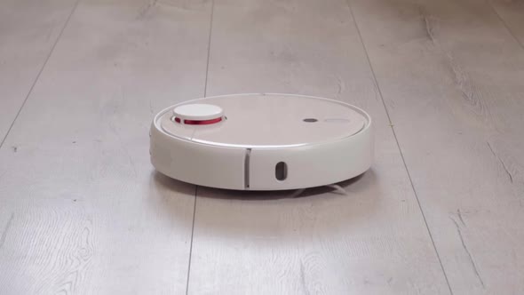 Robot vacuum cleaner vacuuming the floor in the room. Smart home with automated devices