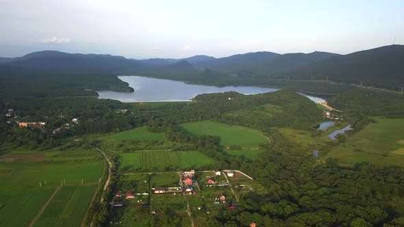 Drone View of Smooth Water and a Dam Surrounded By Green Hills