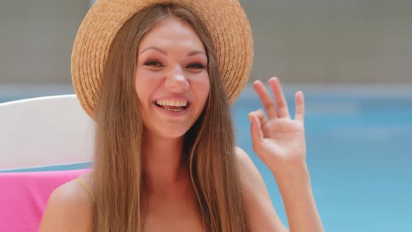 Happy Caucasian Woman in Fashionable Straw Hat Gesturing Ok Smiling with White Teeth Looking at