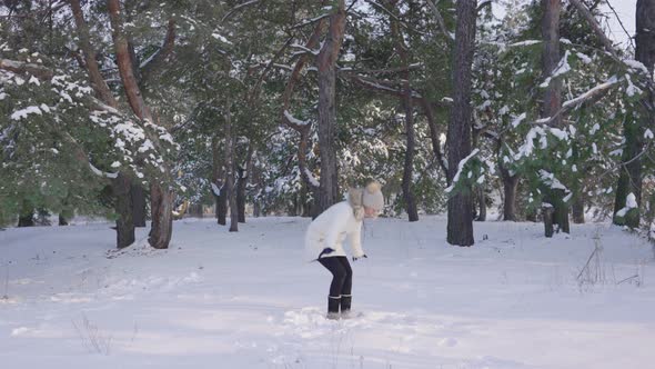 Happy Cute Girl in Warm Winter Clothes Jumping Having Fun and Throwing Snow