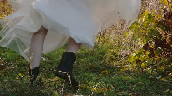 Young beautiful blonde in a white dress rotates and waving her dress on a meadow in the forest. Slow