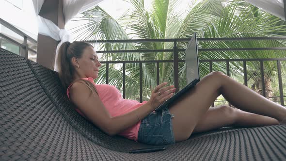 Freelancer with Ponytail in Shorts Leans on Lounger Back