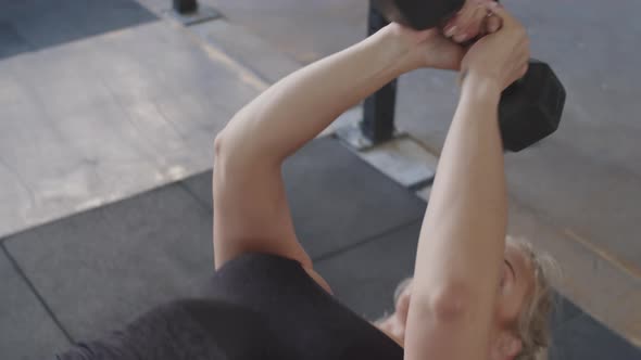 Woman Doing Lying Triceps Extensions with Dumbbell on Gym Bench