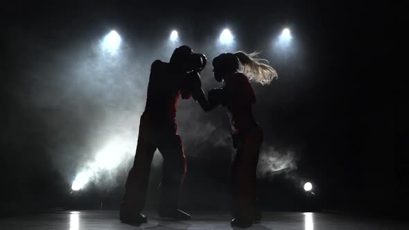 Girl Is Kicking a Guy with Their Sparring Kickboxing. Light From Behind. Smoke Background