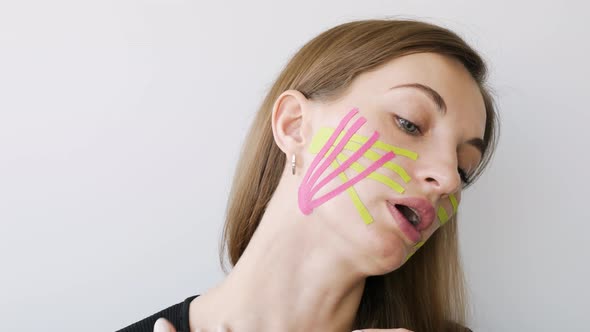 Young Woman Doing the Taping of the Face for Rejuvenation