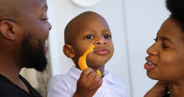 Parents looking at their son while eating bell pepper at home 4k