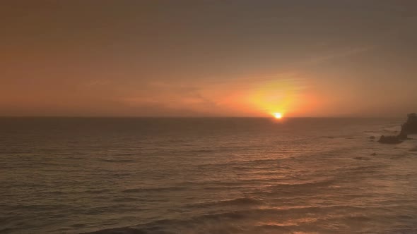 Aerial footage of waves and sunset on the horizon near El Matador Beach, Malibu, Califronia, USA