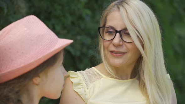 Portrait Mature Blond Mother in Glasses and Her Little Daughter Talking While Sitting on the Bench