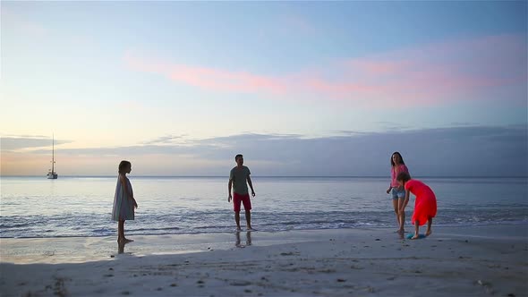 Happy Family Playing with Flying Disk at Beach at Sunset