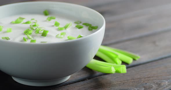 Sour Cream with Chopped Green Onion in Bowl Rotates Slowly