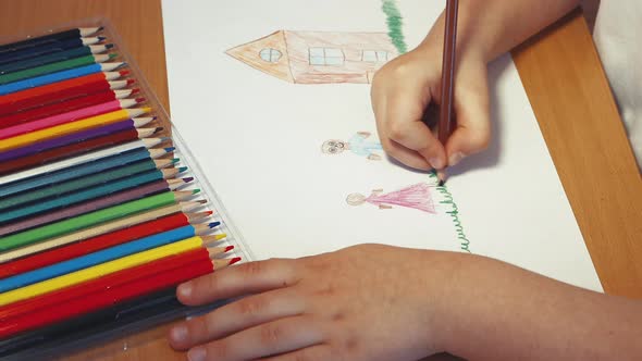 Children's Hands Draw a Family Near the House with a Pencil Closeup