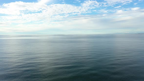 AERIAL: Rippling and Calm blue Baltic Sea with Fluffy Cloudy Sky