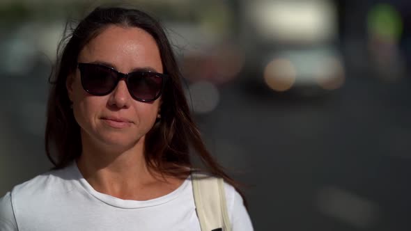 A Close-up Portrait of a Beautiful, Dark-haired, Smiling Middle-aged Woman Wearing Dark Glasses. It