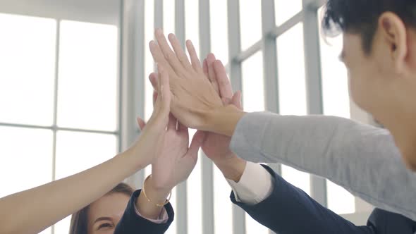 Group of Asian business team people giving hand showing unity and teamwork celebrating success.