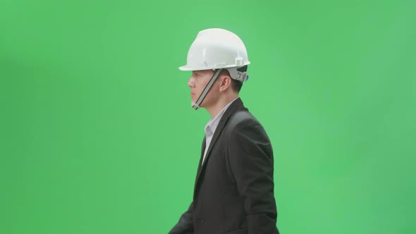 Side View Of Asian Chief Engineer In The Hard Hat Walks On Green Screen Chroma Key