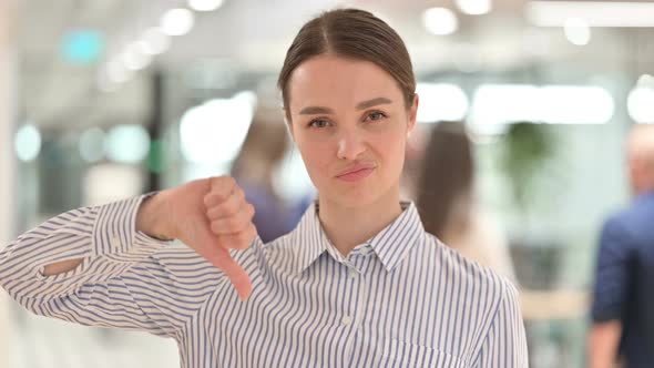 Portrait of Disappointed Young Woman Doing Thumbs Down Sign 