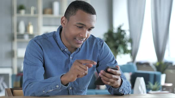 Young African Man Using Smartphone at Workplace