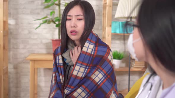 Sick Asian Woman in a Plaid and Gloves with a Temperature Communicates with the Doctor