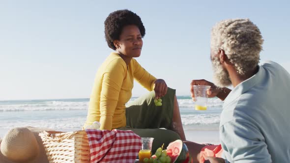 Happy african american couple having picnic on sunny beach