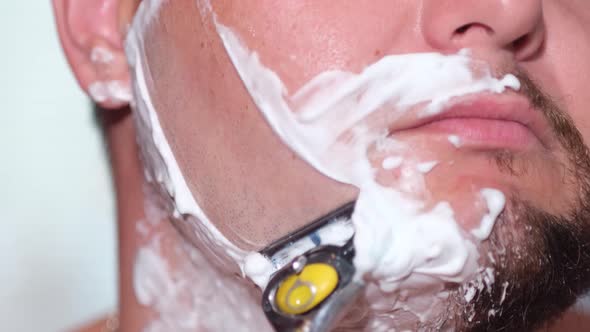 Young Man with a Safety Razor and Shaving Cream on His Face