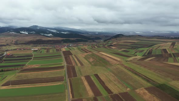 Slow aerial descent towards farmland, Sancraieni, Romania. Ciuc Mountain range