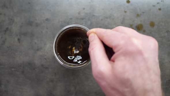 Top View of Person Hand Steering Coffee in a Cup with Spoon