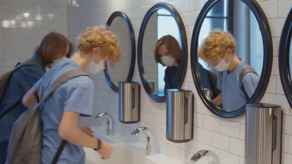 Students in Safety Mask Washing Hands in Modern High School Restroom