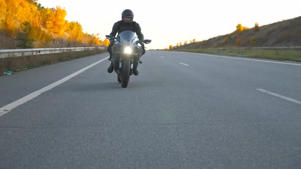 Front View of Young Man in Helmet Riding Fast on Modern Sport Motorbike at Highway