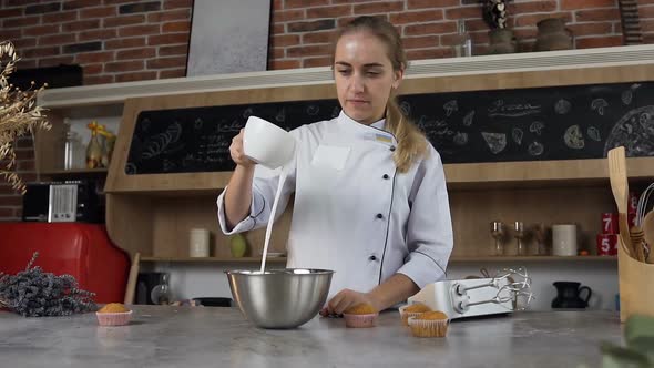 Young Female Confectioner Pouring white Egg Cream in Bowl for Making Sour Cream