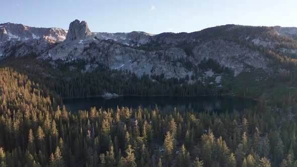 Push-in aerial shot of a secluded alpine lake in the mountains at sunset. 4K