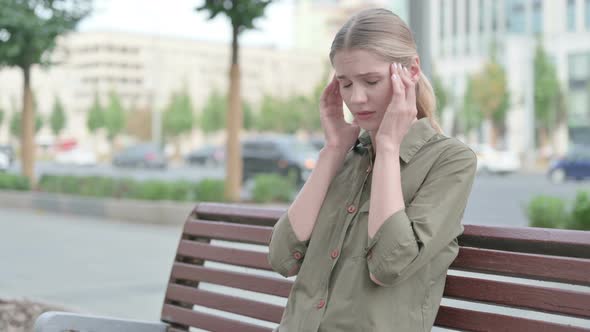 Distressed Woman with Headache Sitting Outdoor on Bench