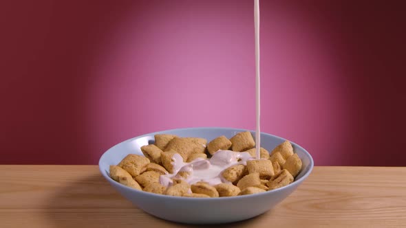 Yogurt is Poured Into a White Bowl of Cornflakes As Pillows