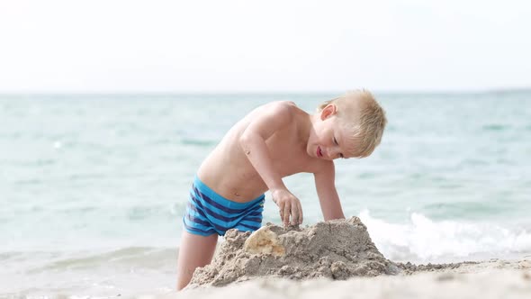 Little Blonde Boy Playing with Sand on Beach Ocean Sea