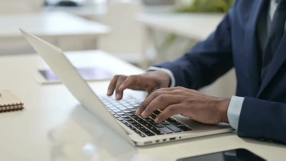 Hands of African Businessman Typing on Laptop Close Up