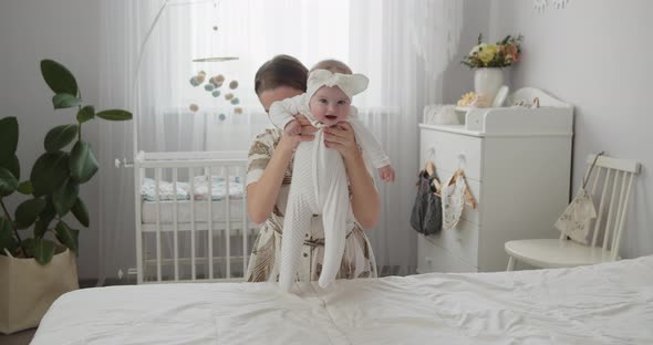 Young Beautiful Mother Lifts Her Adorable Newborn Baby Up and Down