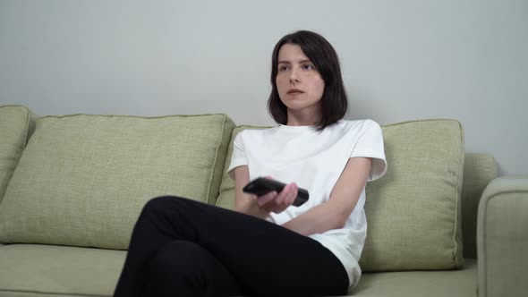 a Woman with a Remote Control Switches Channels and Laughs at the Show