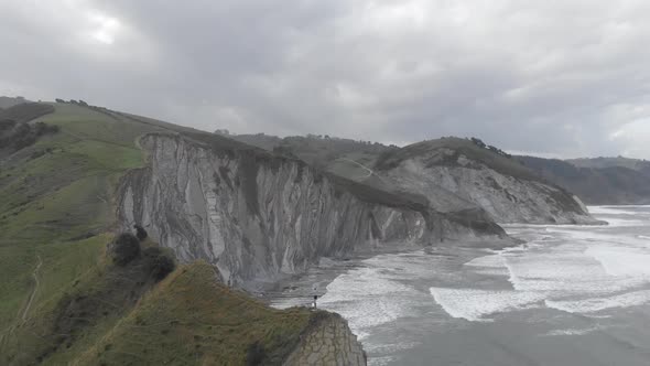 Aerial drone shot of a man over a cliff. Stunning nature landscape. Freedom feeling. Revealing shot.