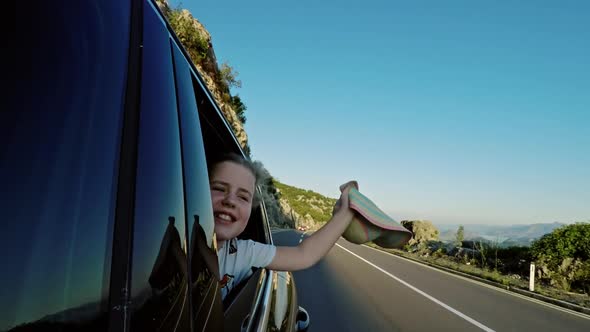 Girl Waving Hat From Car Window