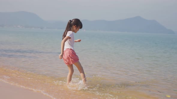 Happy young cute Asian girl running on the beach then jumping on the sea with happiness on holiday.