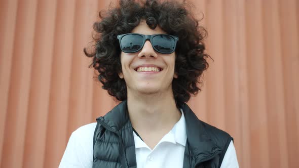 Portrait of Handsome Middle Eastern Teenage Boy Standing Outdoors Wearing Sun Glasses Smiling