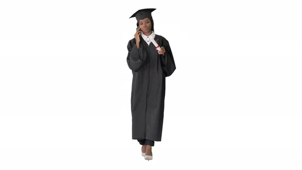 African American Female Student in Graduation Robe Talking on the Phone While Walking on White