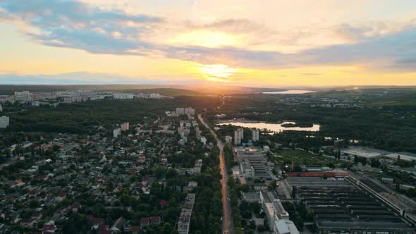 Aerial drone view of Chisinau, Moldova at sunset. Buildings, roads, greenery, cloudy sky, lake