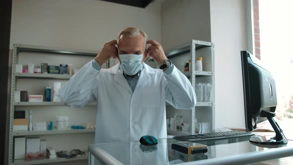Pharmacist Puts on Surgery Mask in the Interior of the Pharmacy