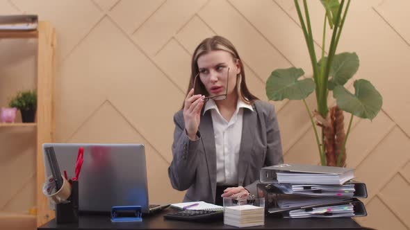 Woman Office Worker Sits on Table and Writes Something in Notebook Takes Off Glasses and Lies Down