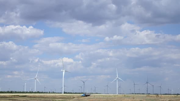 Turbines Spin in the Breeze with Fluffy Floating Clouds. Aerial Survey. Time Lapse