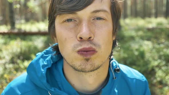 Guy in Blue Jacket Smells and Eats Blueberries in Wood