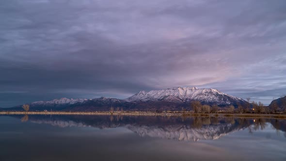 Time lapse of colorful sunrise reflecting in Utah Lake with snow capped mountain