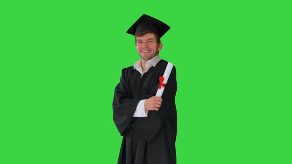 Male Student in Graduation Robe Posing with His Diploma Making Funny Faces on a Green Screen, Chroma